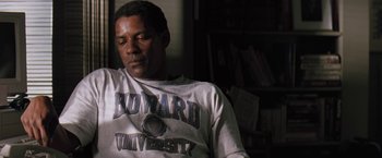 Movie still from “The Pelican Brief” (1993), directed by Alan J. Pakula – A man sitting in front of a bookshelf wearing a white shirt; Medium shot, High angle