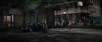Movie still from “The Pelican Brief” (1993), directed by Alan J. Pakula – A woman standing on the sidewalk in front of a building; Wide shot, High angle