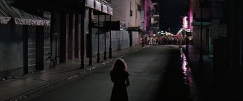 Movie still from “The Pelican Brief” (1993), directed by Alan J. Pakula – A woman standing on the side of a street at night; Extreme Wide shot, High angle