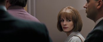 Movie still from “The Pelican Brief” (1993), directed by Alan J. Pakula – A woman looking into a mirror in front of a wall; Close Up shot, Over the shoulder angle