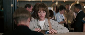 Movie still from “The Pelican Brief” (1993), directed by Alan J. Pakula – A woman sitting at a table with a credit card in front of her face; Close Up shot, Over the shoulder angle