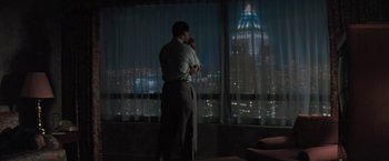Movie still from “The Pelican Brief” (1993), directed by Alan J. Pakula – A man standing in front of a window at night talking on the phone; Wide shot, High angle