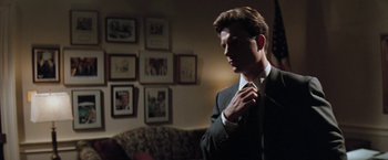 Movie still from “The Pelican Brief” (1993), directed by Alan J. Pakula – A man in a suit adjusting his neck tie; Medium shot, Low angle