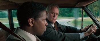 Movie still from “The Pelican Brief” (1993), directed by Alan J. Pakula – Two men sitting in the back seat of a car; Close Up shot, Over the shoulder angle