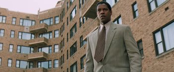 Movie still from “The Pelican Brief” (1993), directed by Alan J. Pakula – A man in a suit and tie standing in front of a building; Medium shot, Low angle