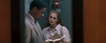 Movie still from “The Pelican Brief” (1993), directed by Alan J. Pakula – A man and a woman are looking at a book; Medium shot, Over the shoulder angle
