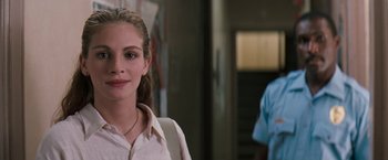 Movie still from “The Pelican Brief” (1993), directed by Alan J. Pakula – A young woman with a necklace standing next to a man; Close Up shot, Over the shoulder angle