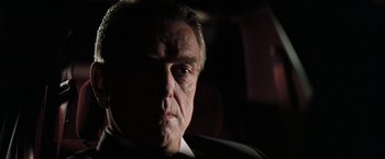 Movie still from “The Pelican Brief” (1993), directed by Alan J. Pakula – An older man in a suit and tie looking at the camera; Close Up shot, Low angle