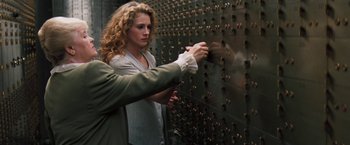 Movie still from “The Pelican Brief” (1993), directed by Alan J. Pakula – A woman and a man working together on a wall; Medium shot, Low angle