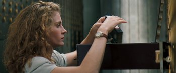 Movie still from “The Pelican Brief” (1993), directed by Alan J. Pakula – A woman looking at her watch while sitting on a chair; Close Up shot, Low angle