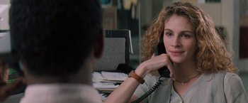 Movie still from “The Pelican Brief” (1993), directed by Alan J. Pakula – A woman sitting in front of a man on the phone; Close Up shot, Over the shoulder angle