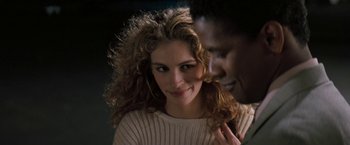 Movie still from “The Pelican Brief” (1993), directed by Alan J. Pakula – A man and a woman smiling for the camera; Close Up shot, Over the shoulder angle