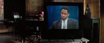 Movie still from “The Pelican Brief” (1993), directed by Alan J. Pakula – A television screen showing a man in a suit and tie; Close Up shot, Over the shoulder angle