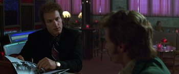 Movie still from “The People vs. Larry Flynt” (1996), directed by Milos Forman – A man sitting at a table talking to another man in front of him; Close Up shot, Over the shoulder angle