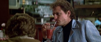 Movie still from “The People vs. Larry Flynt” (1996), directed by Milos Forman – A man sitting at a table with a drink in front of him; Close Up shot, Over the shoulder angle