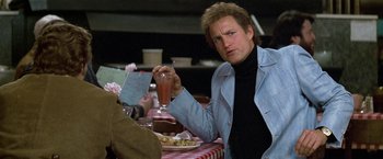 Movie still from “The People vs. Larry Flynt” (1996), directed by Milos Forman – A man sitting at a table holding a drink; Medium shot, Over the shoulder angle