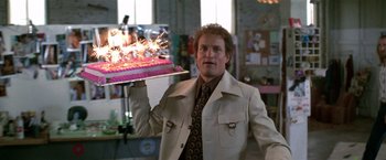 Movie still from “The People vs. Larry Flynt” (1996), directed by Milos Forman – A man holding a cake with a sparkler on top of it; Medium shot, Over the shoulder angle