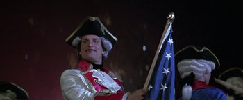 Movie still from “The People vs. Larry Flynt” (1996), directed by Milos Forman – A man wearing a hat and holding an american flag; Medium shot, Low angle