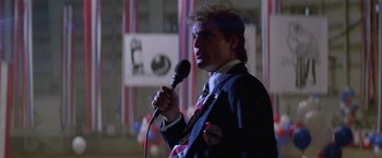 Movie still from “The People vs. Larry Flynt” (1996), directed by Milos Forman – A man holding a microphone and wearing a suit and tie; Medium shot, Low angle