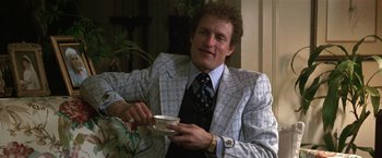 Movie still from “The People vs. Larry Flynt” (1996), directed by Milos Forman – A man wearing a suit and tie eating a bowl of food; Medium shot, Low angle