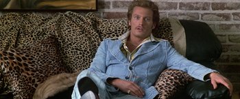 Movie still from “The People vs. Larry Flynt” (1996), directed by Milos Forman – A man sitting on top of a leopard print couch; Medium shot, High angle