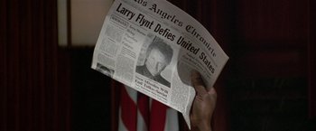 Movie still from “The People vs. Larry Flynt” (1996), directed by Milos Forman – A person holding up a newspaper in front of an american flag; Close Up shot, Low angle