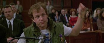 Movie still from “The People vs. Larry Flynt” (1996), directed by Milos Forman – A man in a green jacket is standing in front of a microphone; Close Up shot, Over the shoulder angle