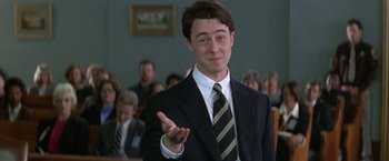 Movie still from “The People vs. Larry Flynt” (1996), directed by Milos Forman – A man in a suit and tie in front of a group of people; Medium shot, Low angle