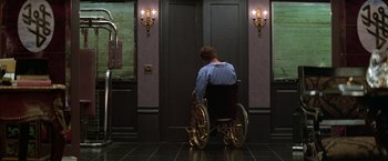 Movie still from “The People vs. Larry Flynt” (1996), directed by Milos Forman – A man sitting in a wheel chair in front of a door; Wide shot, High angle