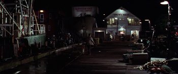 Movie still from “The Perfect Storm” (2000), directed by Wolfgang Petersen – A person standing on a dock at night; Extreme Wide shot, High angle
