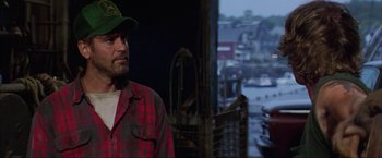 Movie still from “The Perfect Storm” (2000), directed by Wolfgang Petersen – A man wearing a green hat standing in front of a screen; Close Up shot, Over the shoulder angle