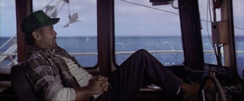 Movie still from “The Perfect Storm” (2000), directed by Wolfgang Petersen – A man sitting on a boat looking out the window; Medium shot, High angle