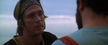 Movie still from “The Perfect Storm” (2000), directed by Wolfgang Petersen – A man wearing a bandana and a headband talking to another man; Close Up shot, Over the shoulder angle
