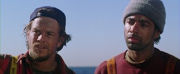 Movie still from “The Perfect Storm” (2000), directed by Wolfgang Petersen – Two men standing next to each other on the beach; Close Up shot, Low angle
