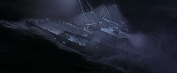 Movie still from “The Perfect Storm” (2000), directed by Wolfgang Petersen – A boat in the water at night with a light shining on it; Extreme Wide shot, High angle