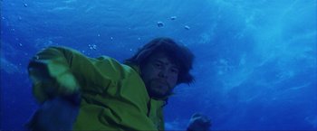 Movie still from “The Perfect Storm” (2000), directed by Wolfgang Petersen – A man in a yellow jacket is underwater; Close Up shot, Overhead angle