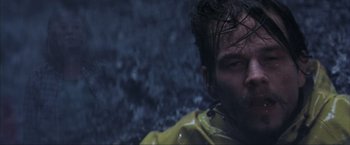 Movie still from “The Perfect Storm” (2000), directed by Wolfgang Petersen – A man in a yellow raincoat is standing in the rain; Close Up shot, Overhead angle