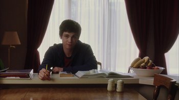 Movie still from “The Perks of Being a Wallflower” (2012), directed by Stephen Chbosky – A man sitting at a table with papers and a pen; Medium shot, Over the shoulder angle