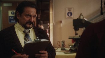 Movie still from “The Perks of Being a Wallflower” (2012), directed by Stephen Chbosky – A man in a brown jacket holding a clipboard in a room; Close Up shot, Over the shoulder angle