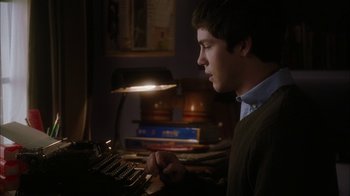 Movie still from “The Perks of Being a Wallflower” (2012), directed by Stephen Chbosky – A young man using an old typewriter in a dark room; Medium shot, Over the shoulder angle