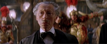 Movie still from “The Phantom of the Opera” (2004), directed by Joel Schumacher – An older man with a mustache and a bow tie; Close Up shot, Low angle