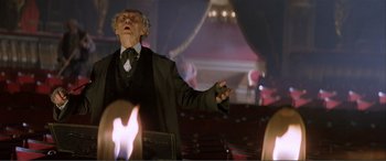 Movie still from “The Phantom of the Opera” (2004), directed by Joel Schumacher – An old man in a black suit and a white tie; Medium shot, Low angle