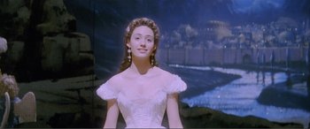 Movie still from “The Phantom of the Opera” (2004), directed by Joel Schumacher – A woman in a white dress and long earrings; Medium shot, Low angle
