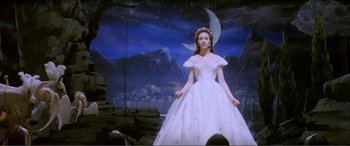 Movie still from “The Phantom of the Opera” (2004), directed by Joel Schumacher – A woman in a white dress standing in front of a moon; Medium shot, Low angle