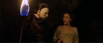 Movie still from “The Phantom of the Opera” (2004), directed by Joel Schumacher – A man and a woman wearing masks in a dark room; Close Up shot, Over the shoulder angle