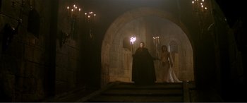 Movie still from “The Phantom of the Opera” (2004), directed by Joel Schumacher – A man and a woman are standing in a castle; Wide shot, Low angle
