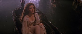 Movie still from “The Phantom of the Opera” (2004), directed by Joel Schumacher – A woman sitting on a chair in a room; Medium shot, High angle