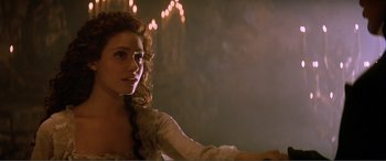 Movie still from “The Phantom of the Opera” (2004), directed by Joel Schumacher – A beautiful woman with long hair sitting in a room; Close Up shot, Over the shoulder angle