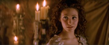 Movie still from “The Phantom of the Opera” (2004), directed by Joel Schumacher – A beautiful young woman with a candle in the background; Close Up shot, Over the shoulder angle