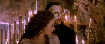Movie still from “The Phantom of the Opera” (2004), directed by Joel Schumacher – A man and a woman wearing a white mask; Close Up shot, Low angle